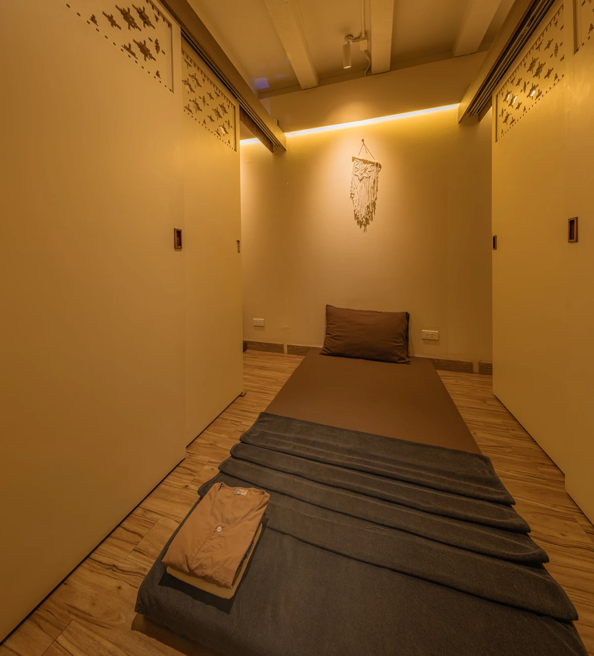 Warm-lit treatment room with folded Thai massage clothes at a licensed massage in Siam Bangkok flagship shop