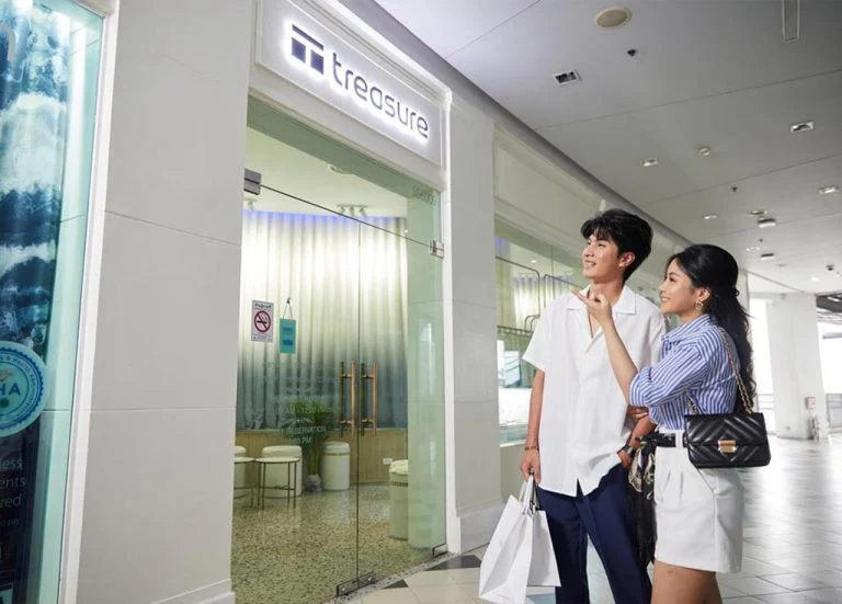 Glass entrance of Treasure Spa on the sixth floor of Siam Square One with two shoppers walking past, a massage in Siam Bangkok