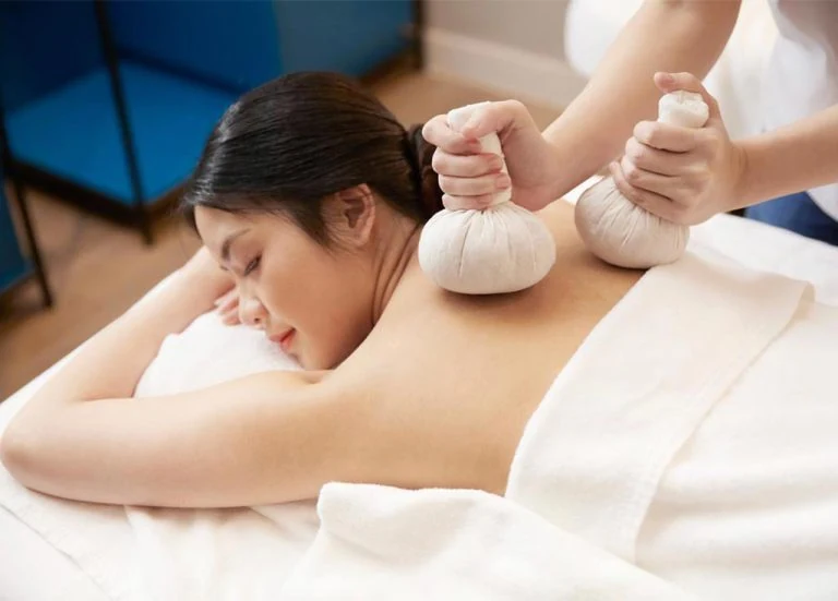 Steamed herbal compress balls on a wooden tray beside a private treatment room, part of a couples massage in Siam Bangkok at Treasure Spa